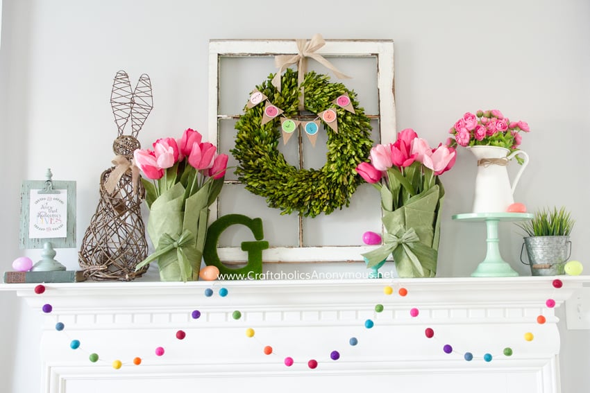 bright and colorful spring mantel with bright pink flowers, colorful garland and boxwood wreath