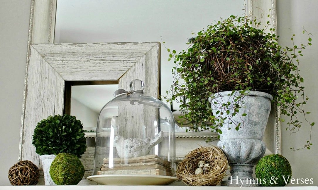 nature inspired mantel with moss balls greenery and glass dome with stone bird