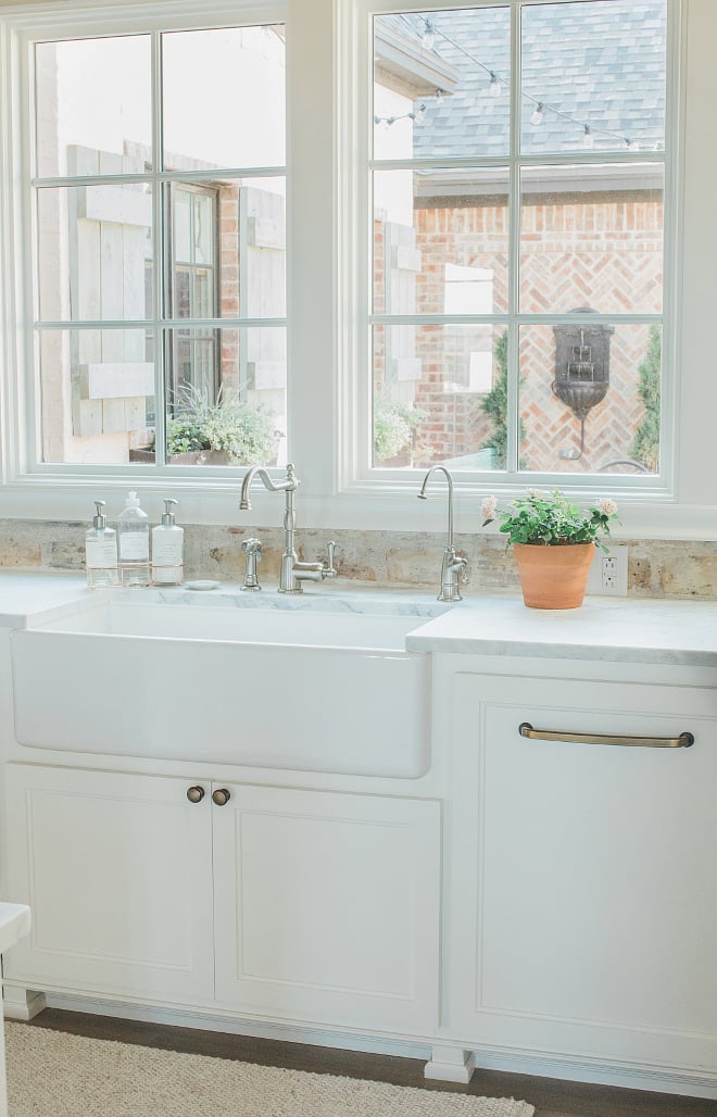 Base kitchen cabinets painted SW Alabaster with a bright white farmhouse sink looking out to a sunny terrace.