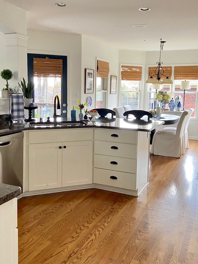 Kitchen cabinets painted Alabaster with black countertops and black cabinet hardware.