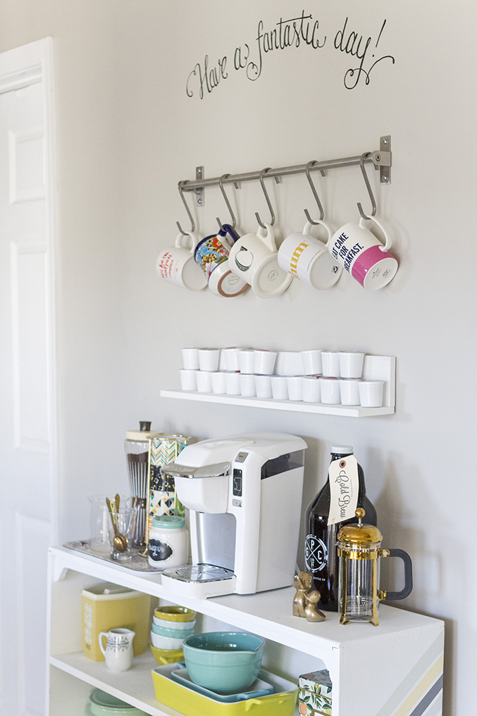 coffee bar with colorful mugs hanging on wall and coffee item on small cart