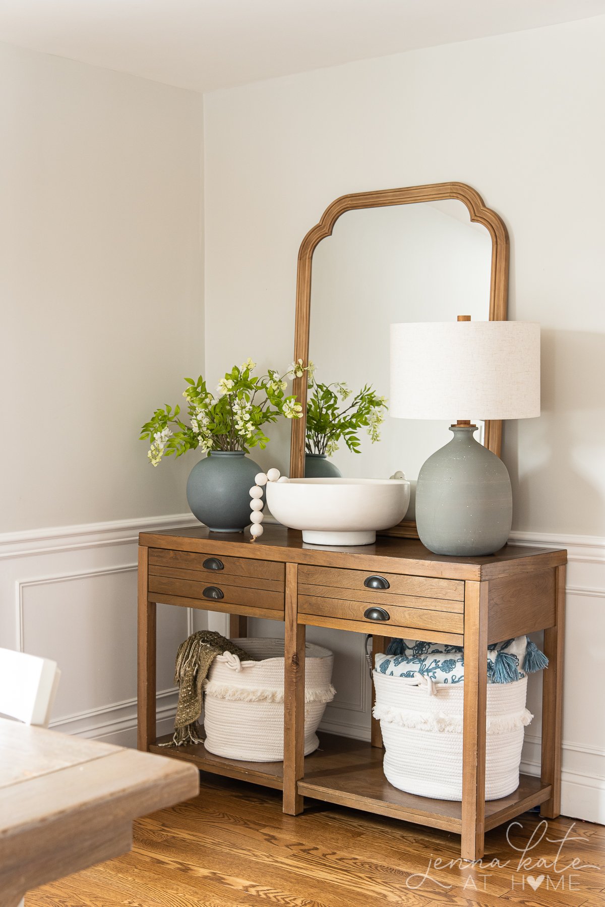 console table with leaning mirror, vase of flowers and a large table lamp