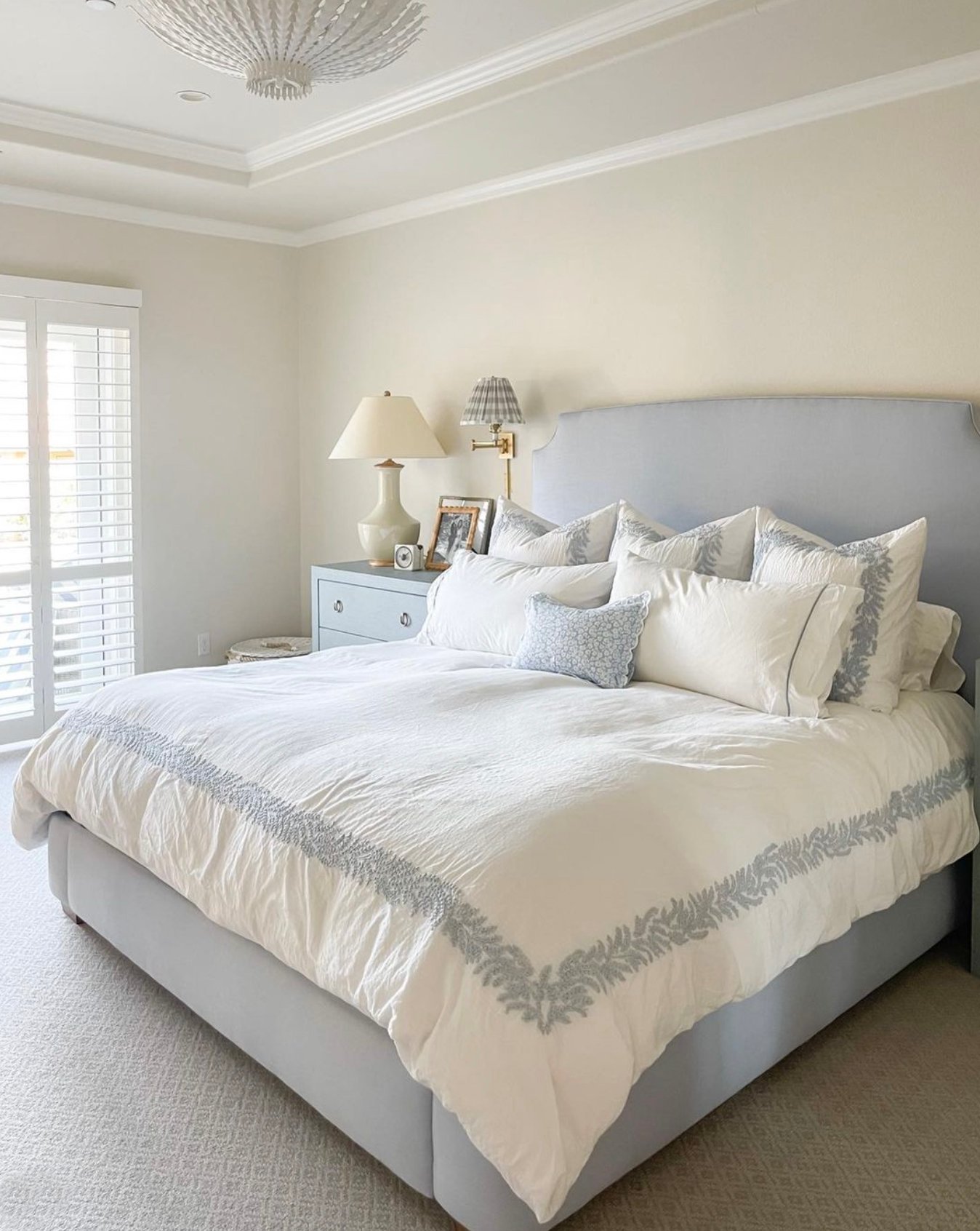 bedroom with a blue fabric bed with white linens and walls painted Shoji White.