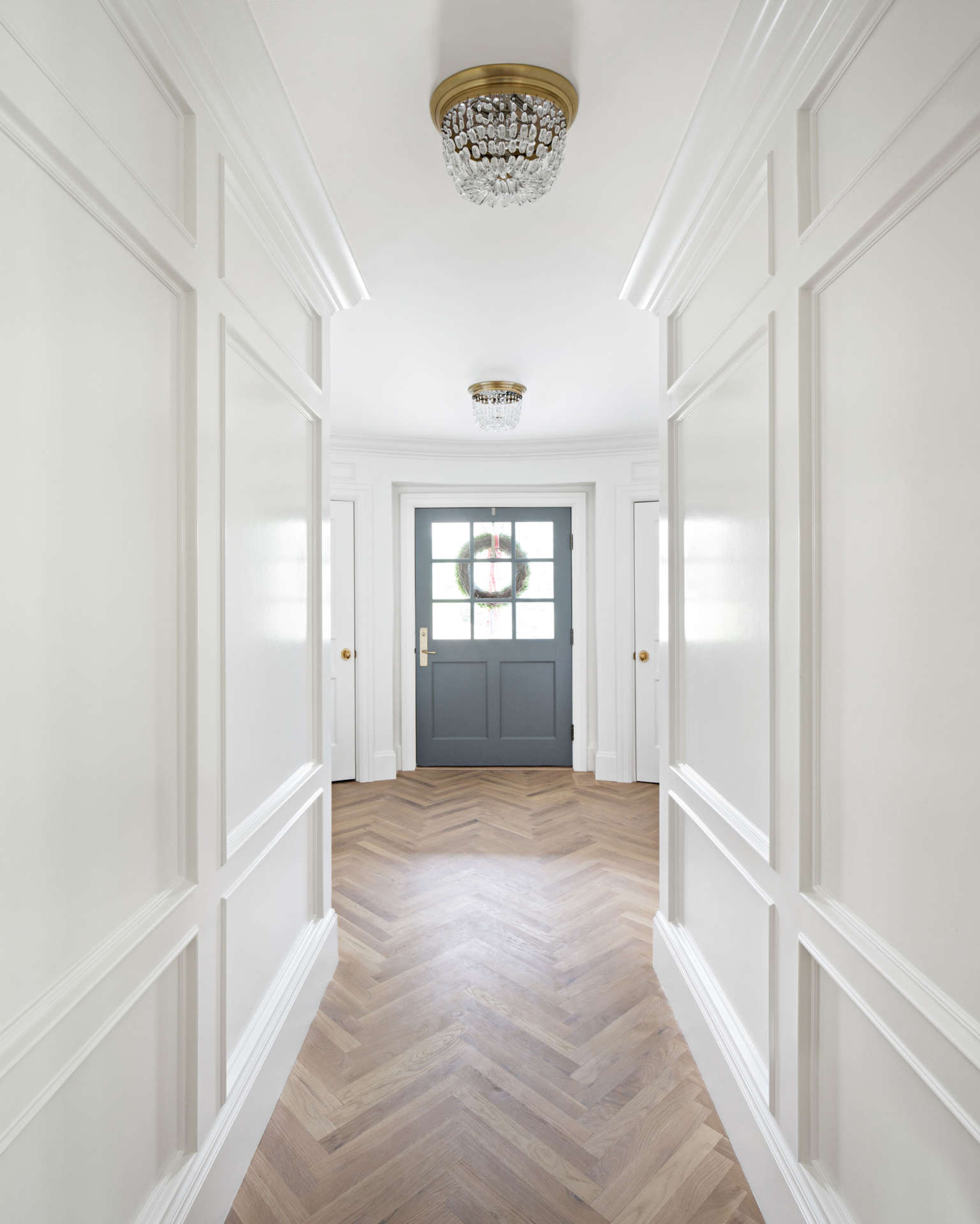 large bright hallway with wainscoting and a black front door.