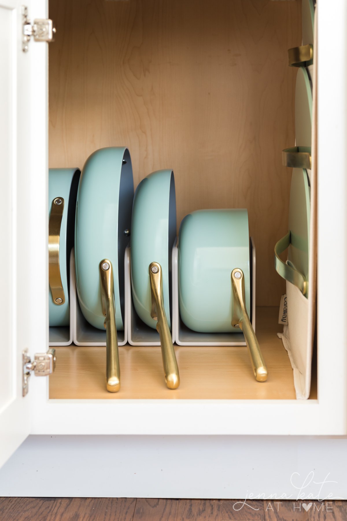 mint green and gold cookware organized inside a kitchen cabinet