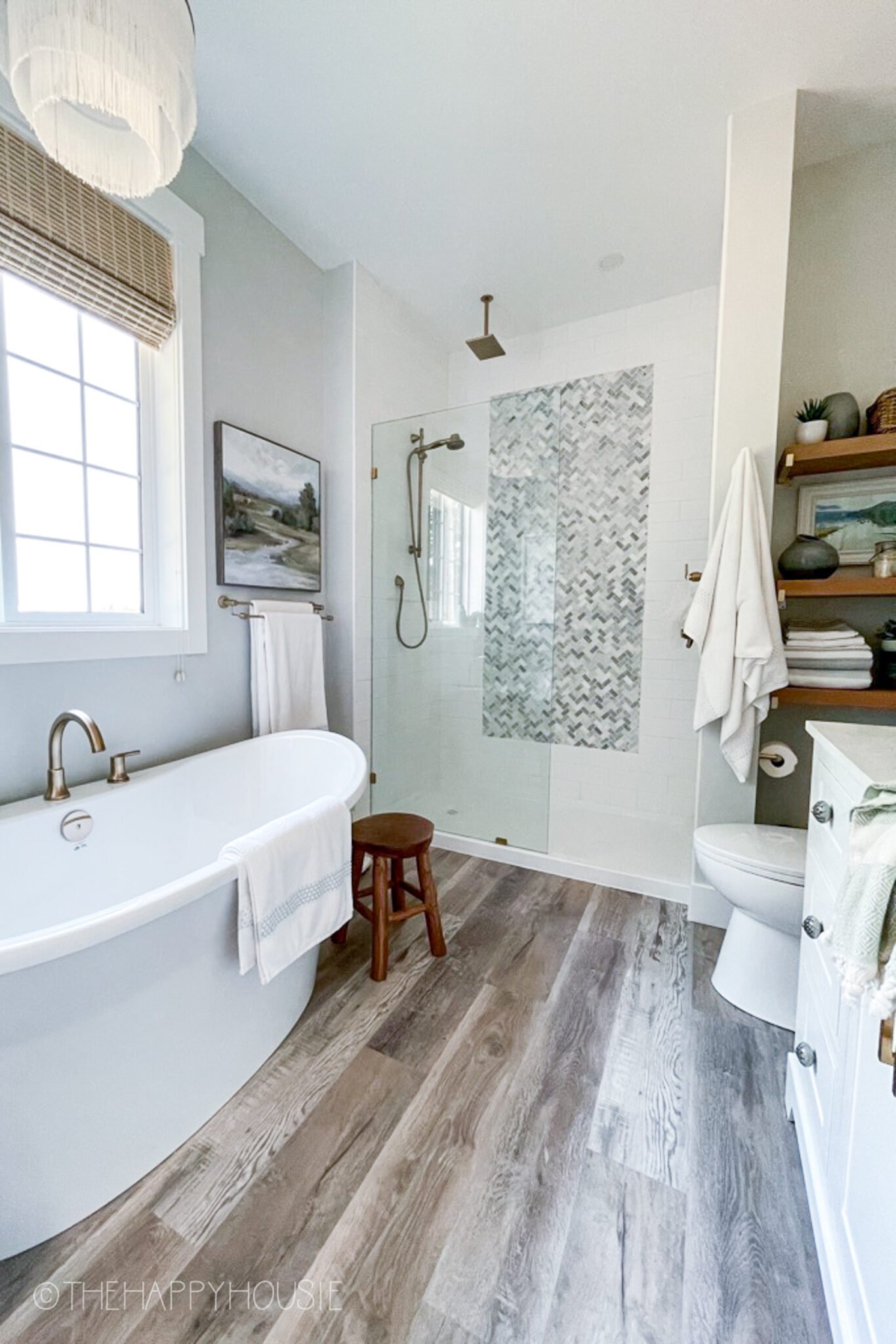 white bathroom witth freestanding tub LVP wood flooring and tiled shower