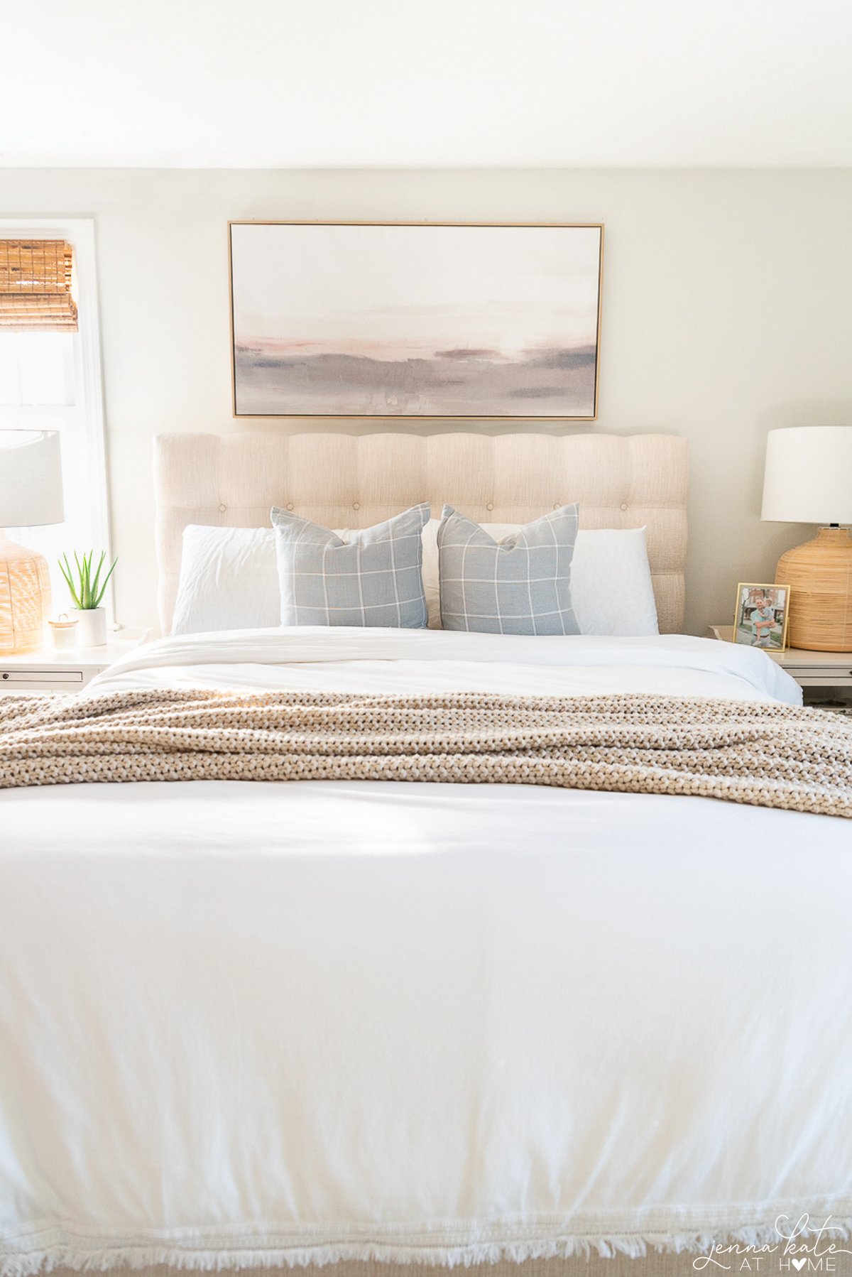 landscape art over a bed with a linen headboard