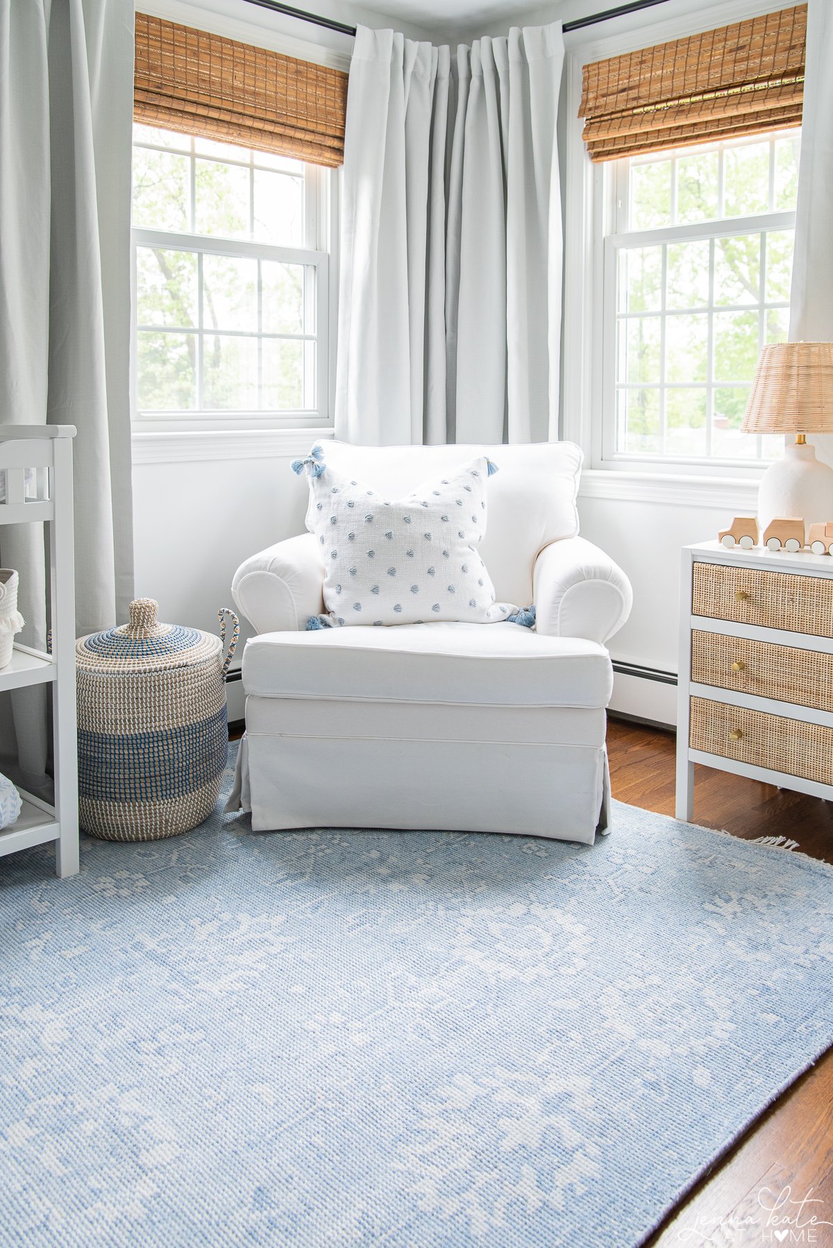 A kids bedroom with a white chair in the corner in between two windows.