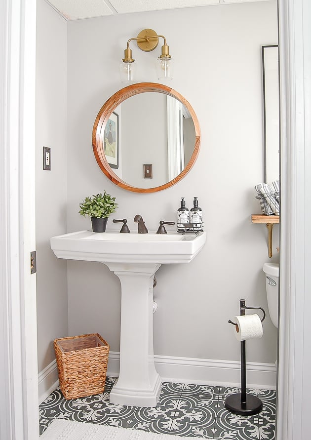 powder room with walls painted on the rocks, black patterned floor tile and white pedestal sink