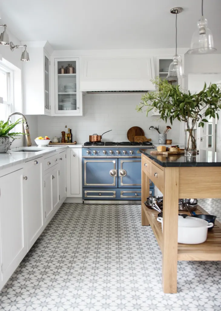 Decorator's White kitchen cabinets in an airy kitchen with blue stove and fun tiled floors