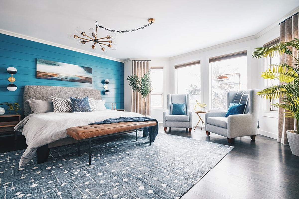 blue rug with white patterns under a bed with bright blue shiplap accent wall