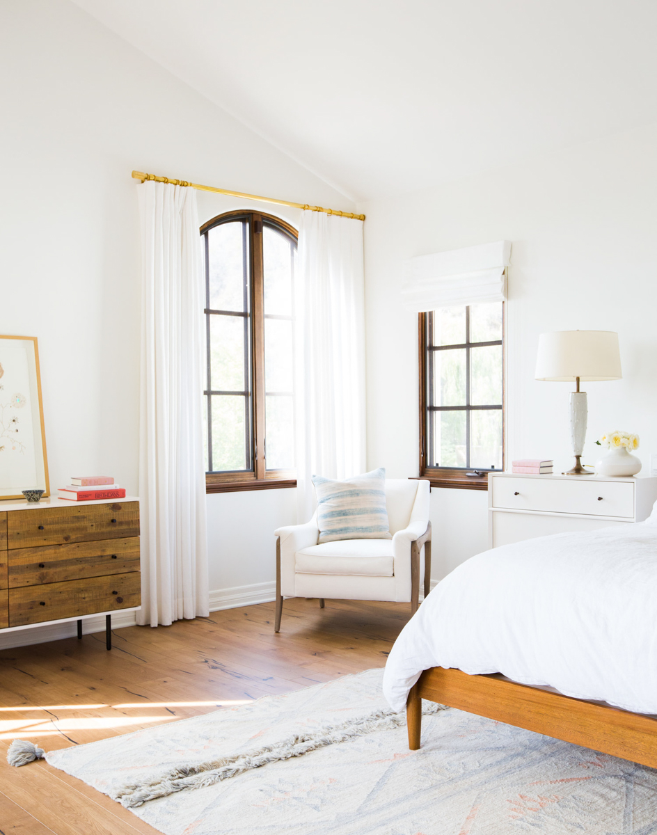 bedroom with white walls, white curtains and natural wood furniture