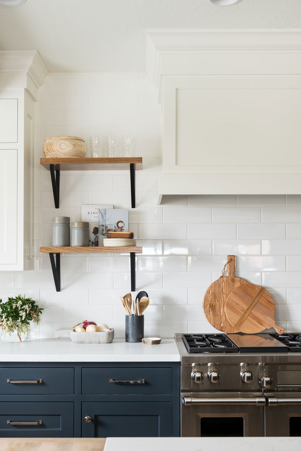 stove wall with subway tile, white shelves and white range hood