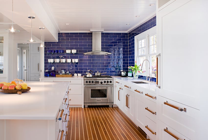 Royal blue kitchen backsplash with white cabinets, wood floors and copper hardware