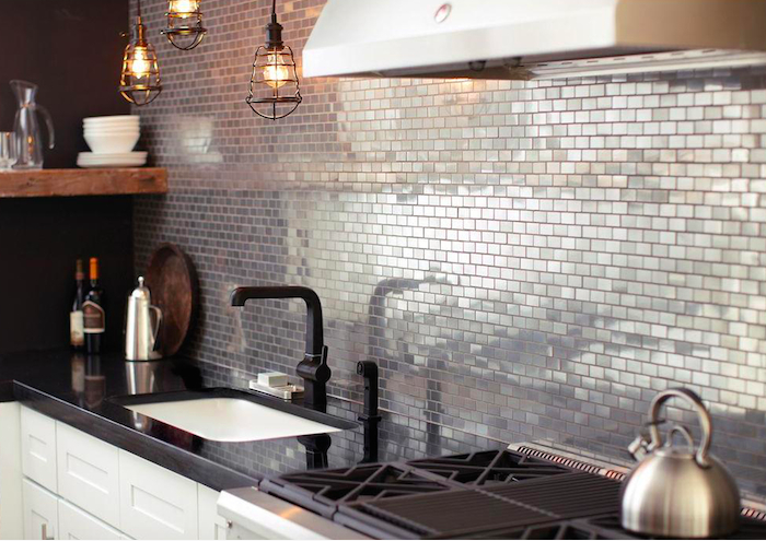 Metal reflective mosaic tile kitchen backsplash with black counters and white cabinets