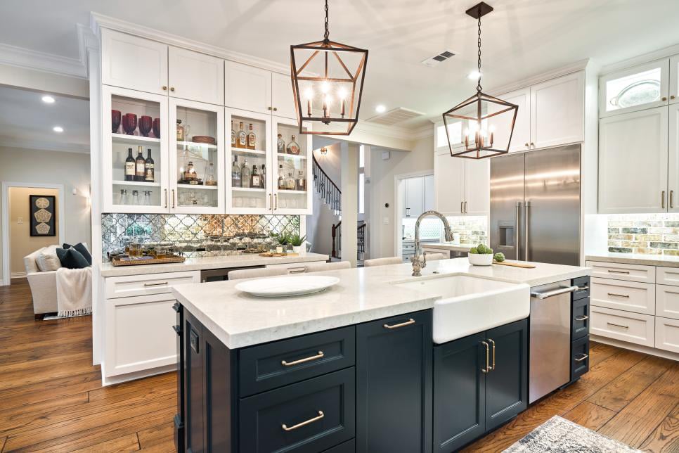 large kitchen with island and mirrored backsplash that go with white cabinetry