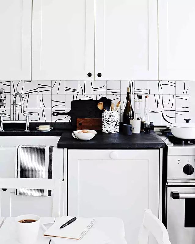 Hand painted white kitchen tiles with black countertop and white cabinets