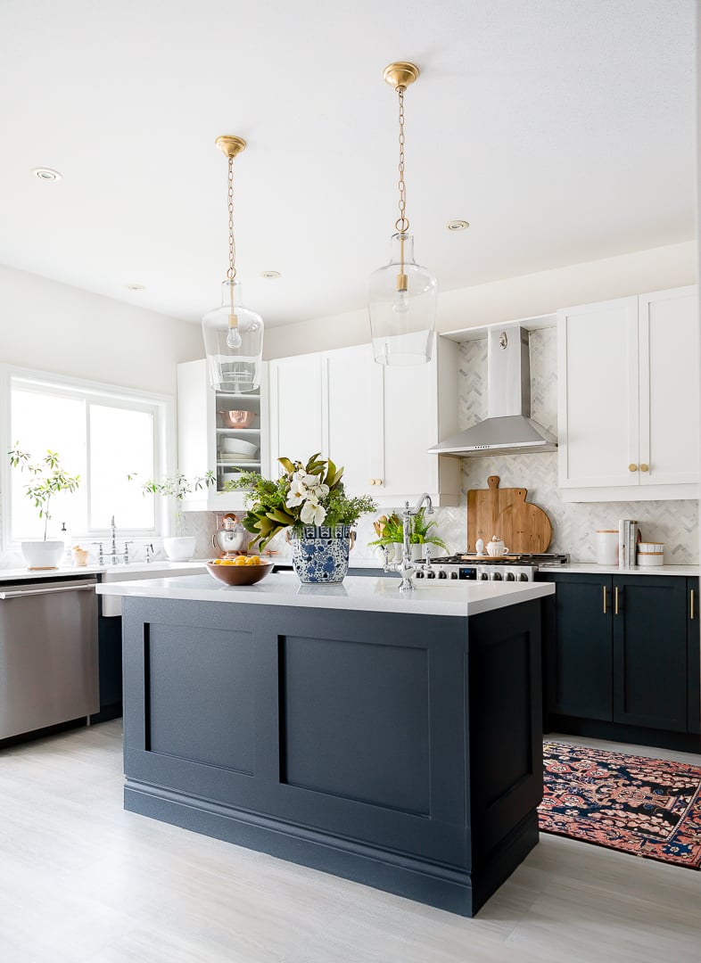 black lower cabinets and white upper cabinets with marble backsplash