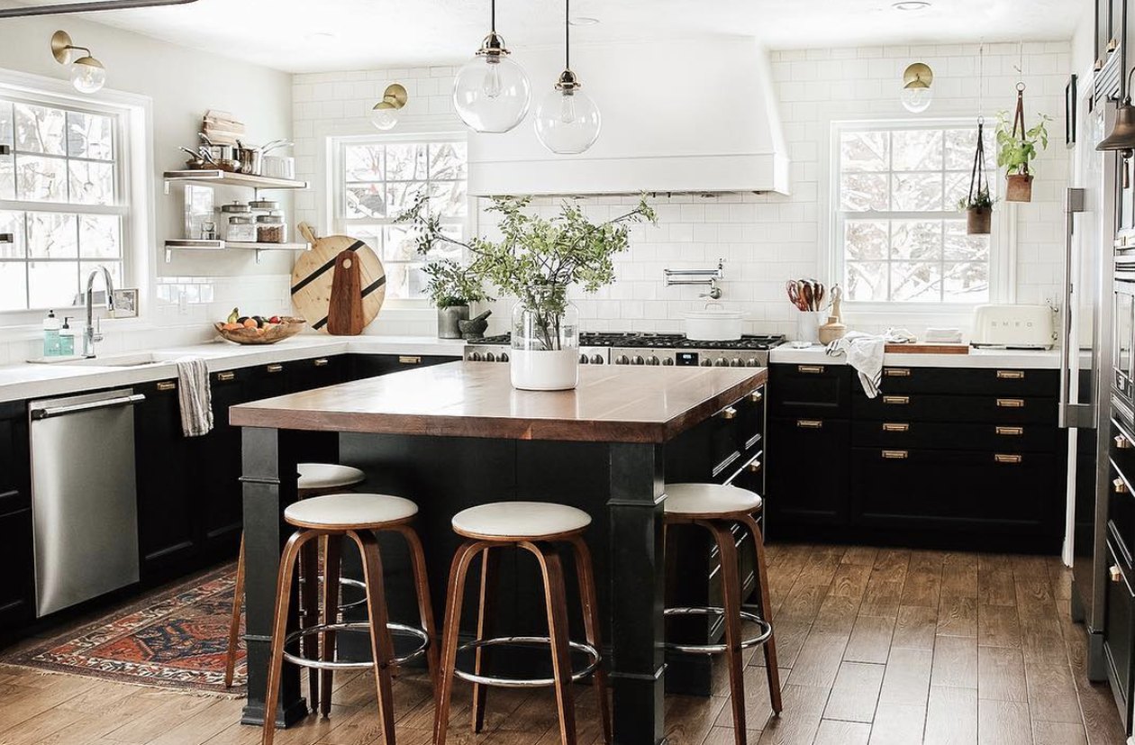 dark lower kitchen cabinets with wooden countertop and white range hood