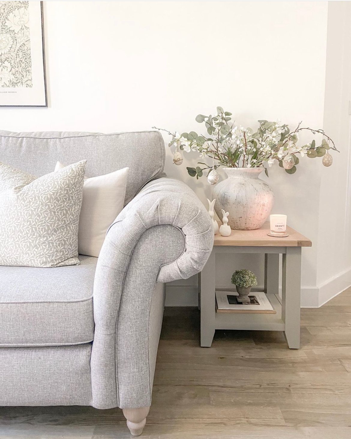 a side table beside a couch with a faux plant resting on it