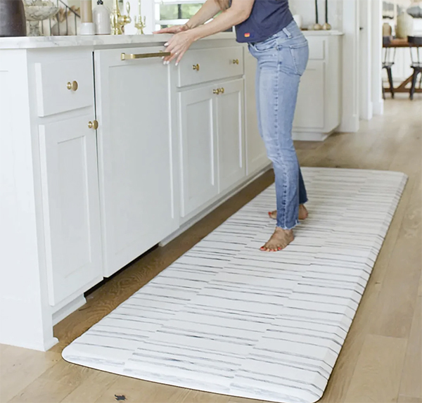 woman emptying dishwasher with standing mat kitchen runner underfoot