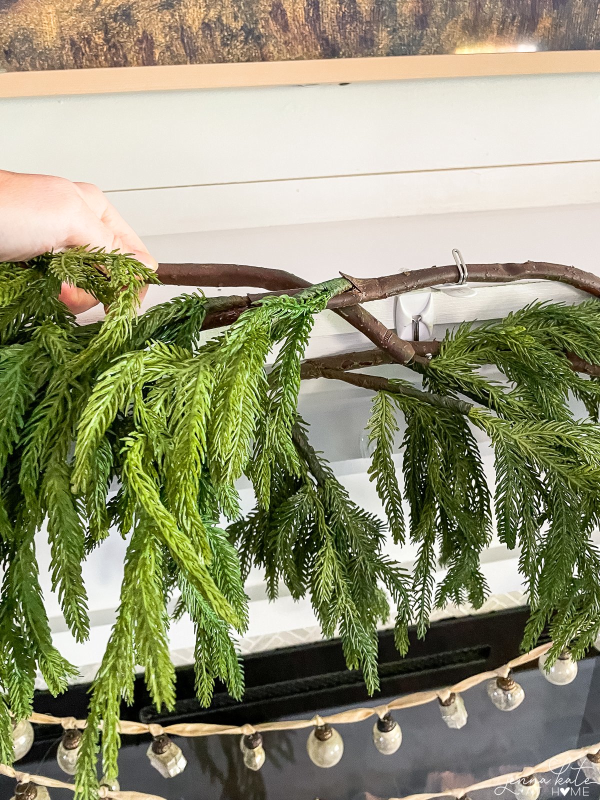 overlapping branches to securely add the third and fourth pieces of garland to the mantel