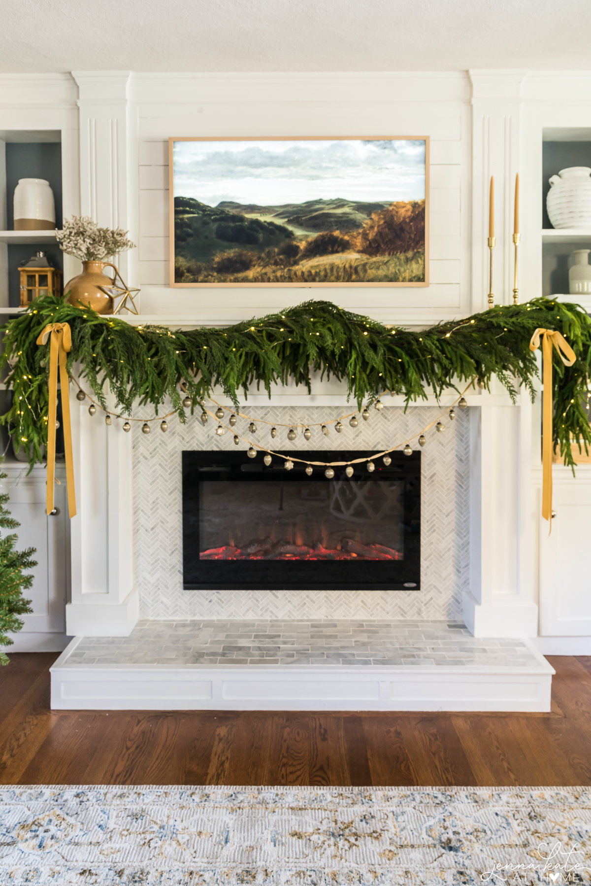 mantel with artificial Norfolk Pine garland draped over it, ribbon on the sides and bells draped underneath