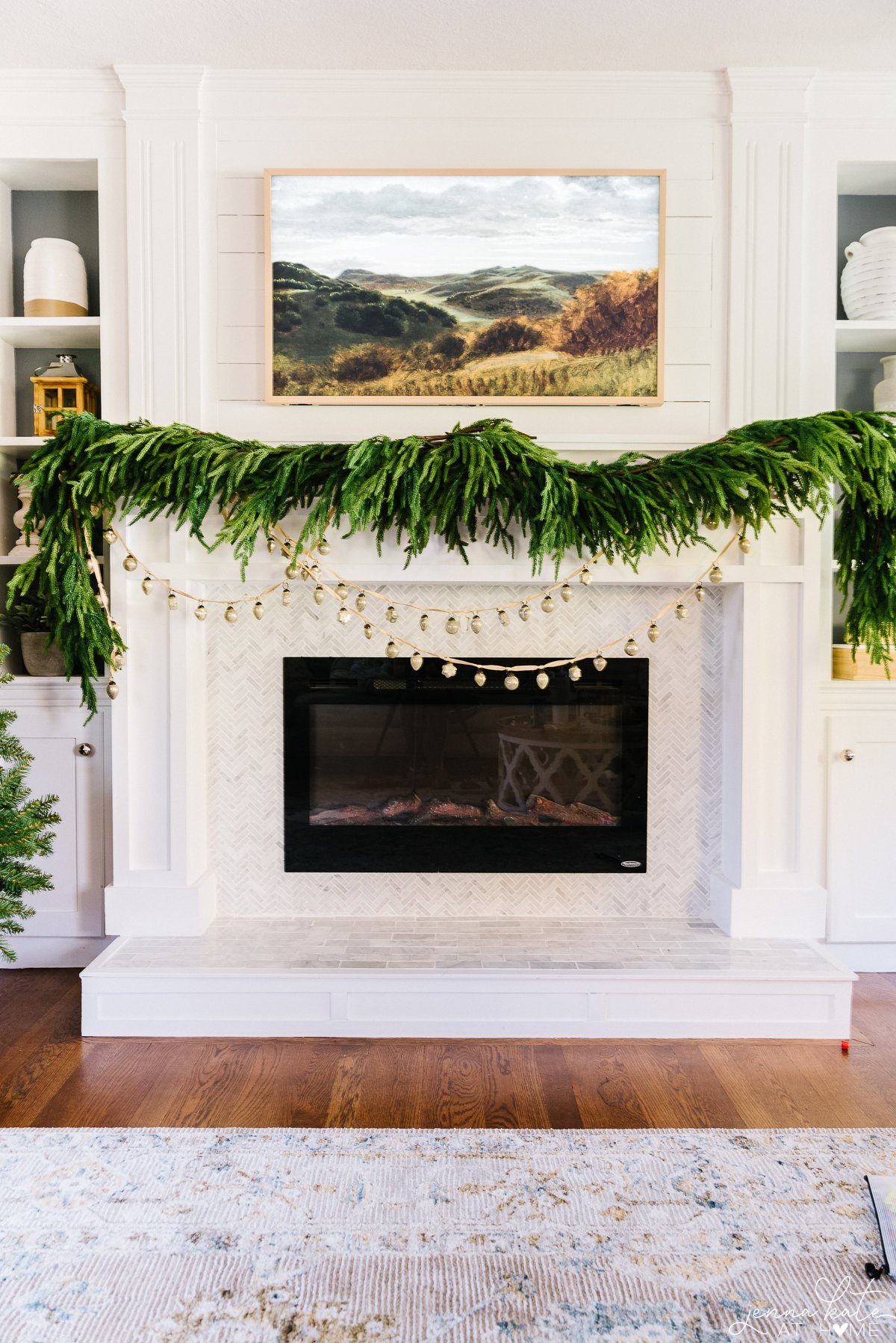 mantel with norfolk pine garland and tv above it