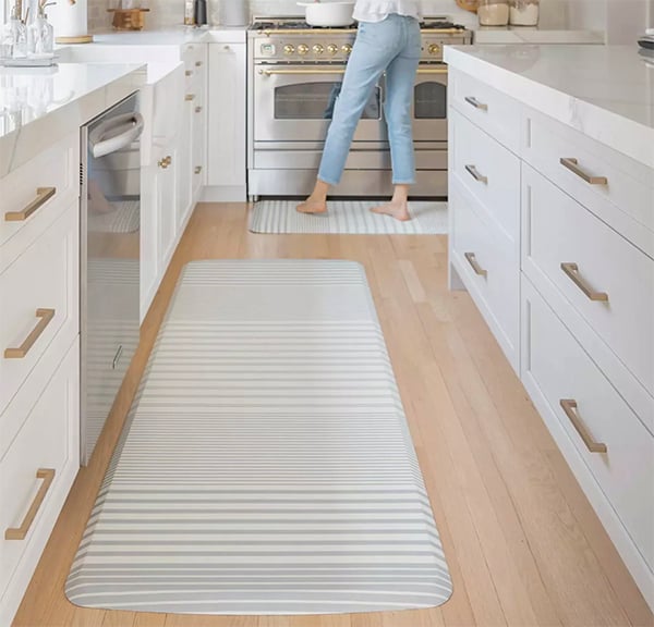 woman cooking at a stove with a grey anti fatigue mat underfoot