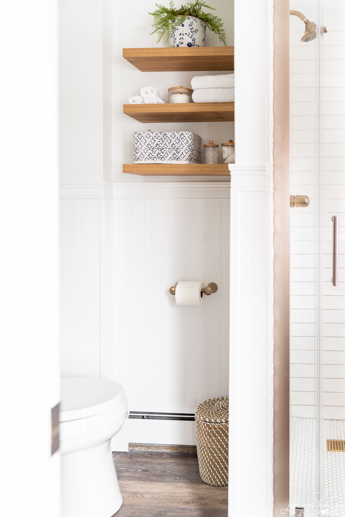 view of the shower, floating shelves and toilet roll holder in the bathroom