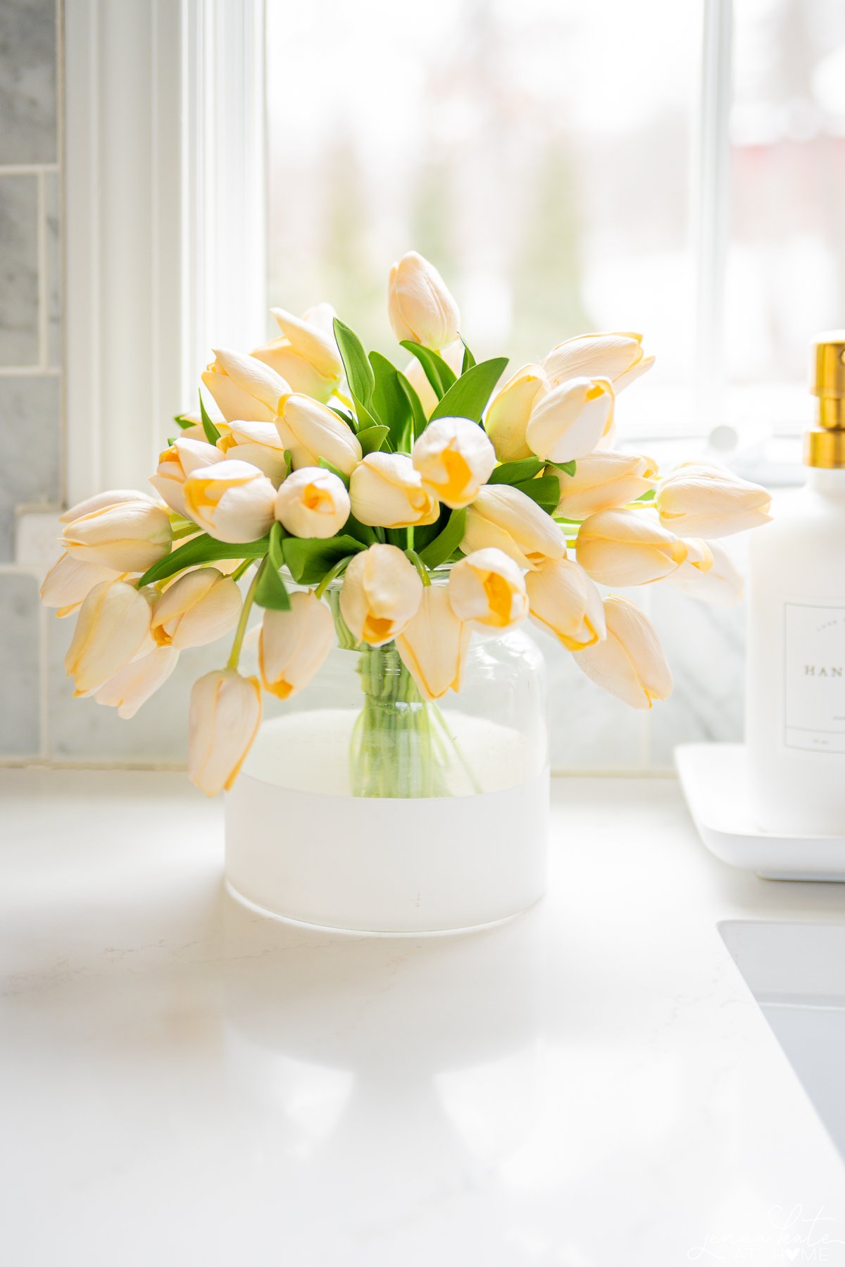 faux white tulips in a clear and white vase