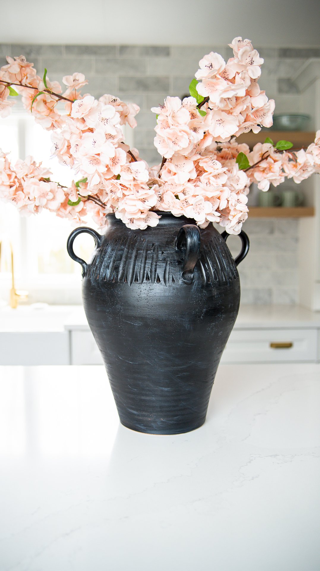 artificial pink cherry blossoms on a large black vase