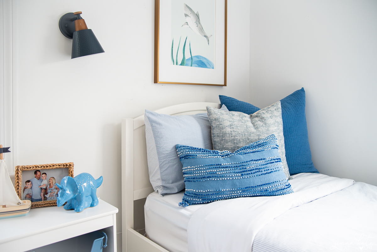 blue accents on a twin bed with reading wall sconce