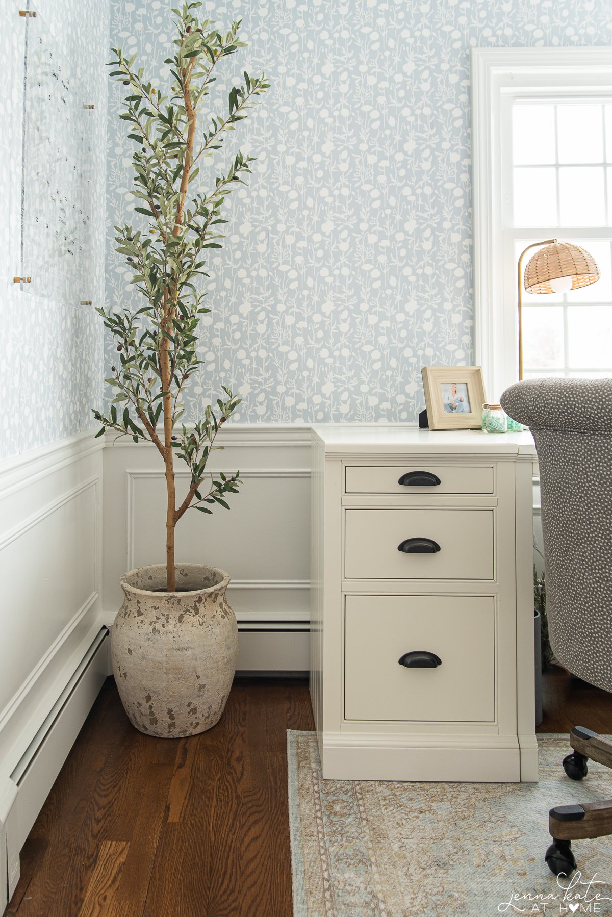 corner of office with a faux olive tree and white desk