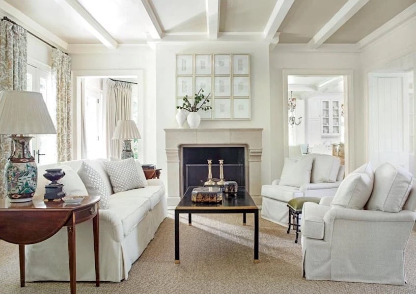 Bright living room painted Linen White on the walls with white couches and a fireplace