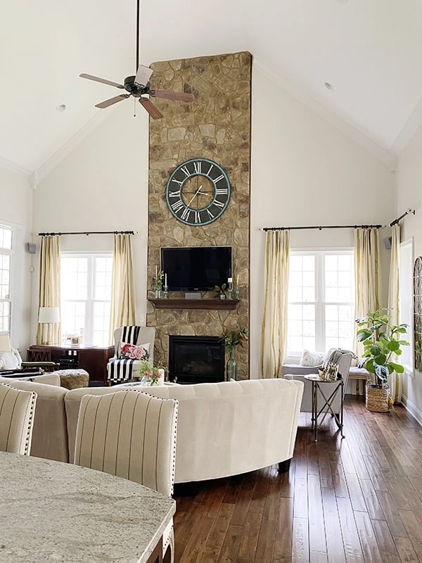 Open living room painted Sherwin Williams Origami White with a large stone fireplace