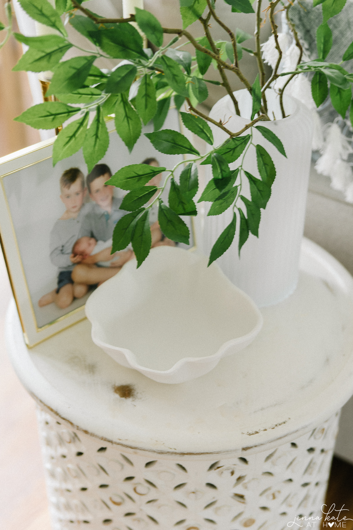 accent table with a scalloped white  bowl and green leafy stems