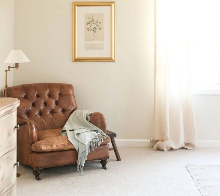 Light and airy bedroom with a leather chair in the corner and Soft Chamois painted walls.