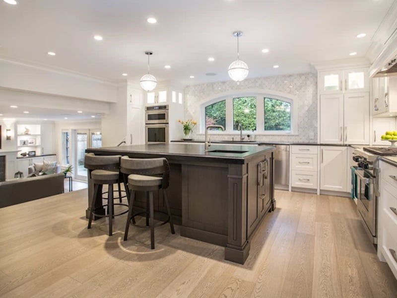 Bright white kitchen with Benjamin Moore Distant Grey kitchen cabinets and a large dark wood island. 