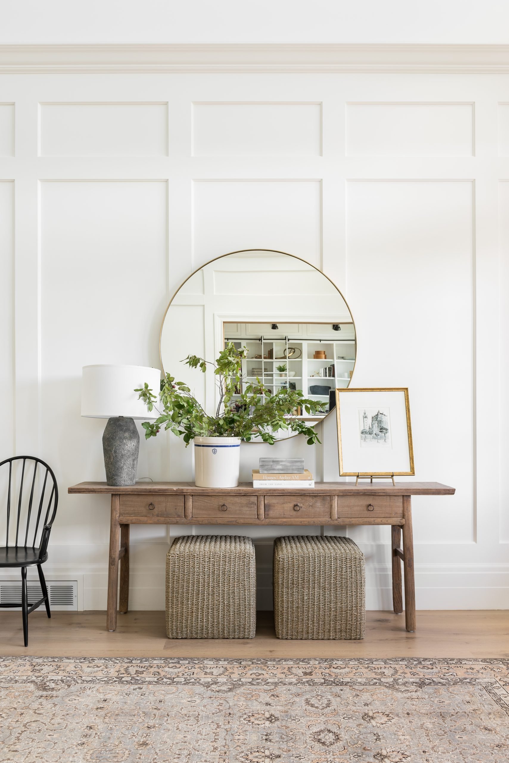 rustic console table decorated with various objects and ottomans underneath