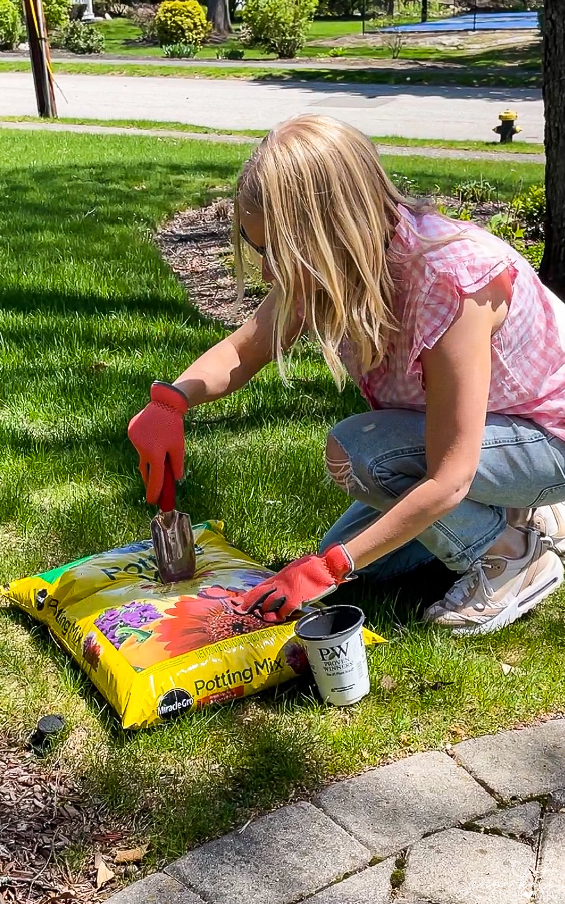 a woman opening a bag of potting mix