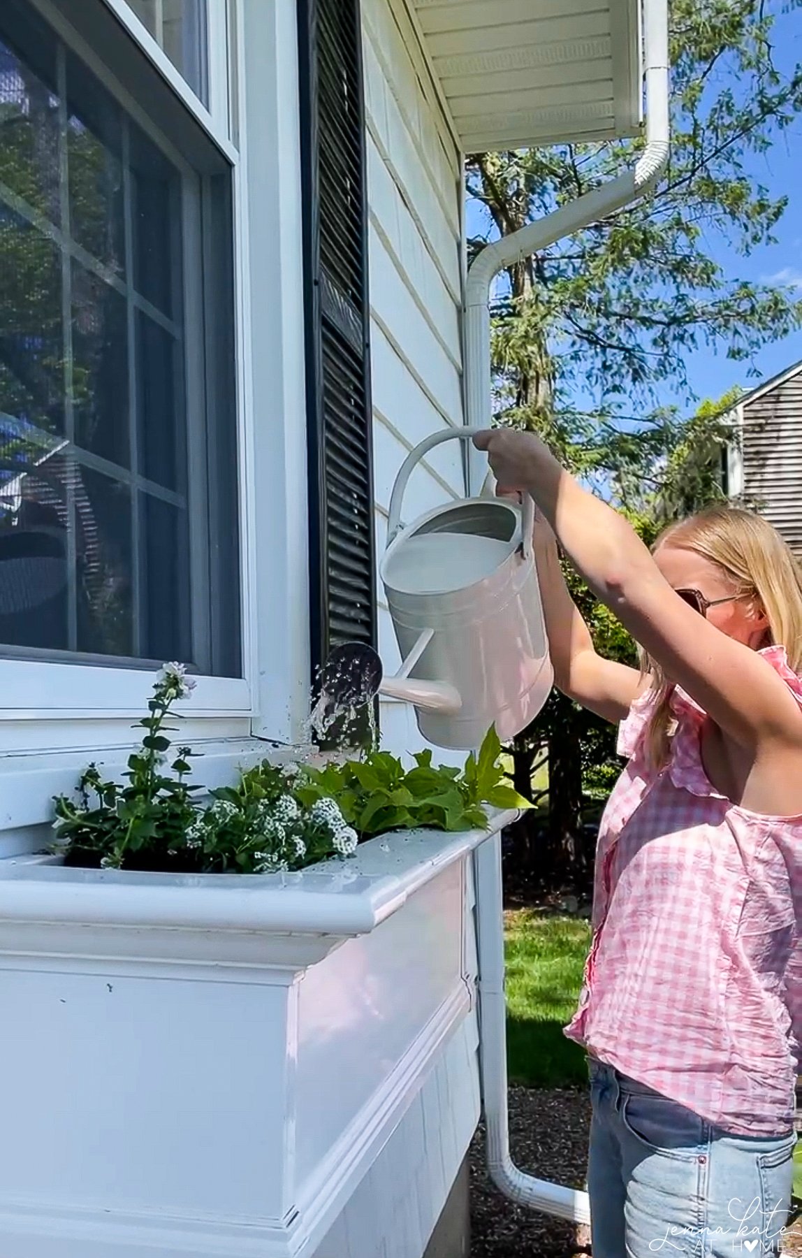 a woman watering plants in a window box