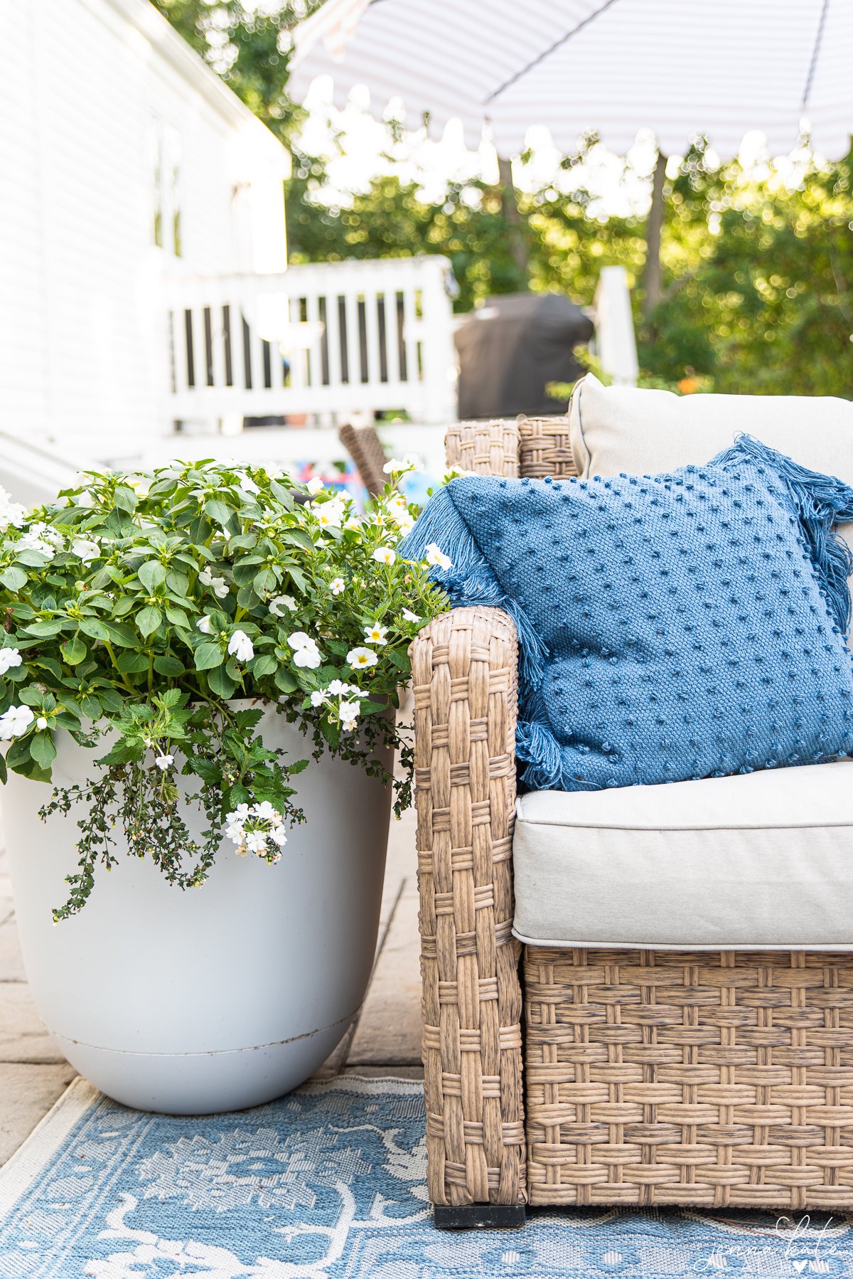 planter next to outdoor sofa overflowing with petunias, calibrachoa and bacopa.