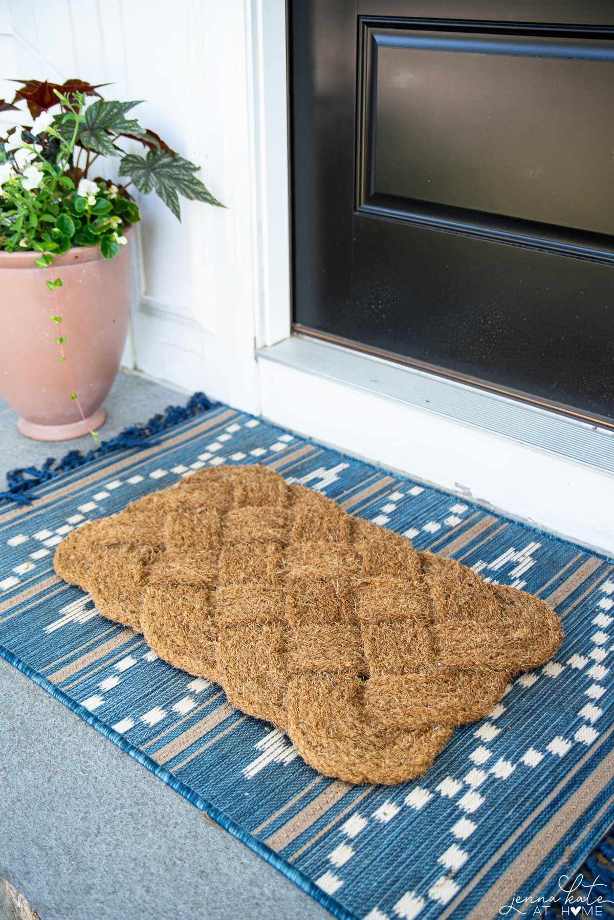 Braided coir doormat from Amazon on top of a blue rug.