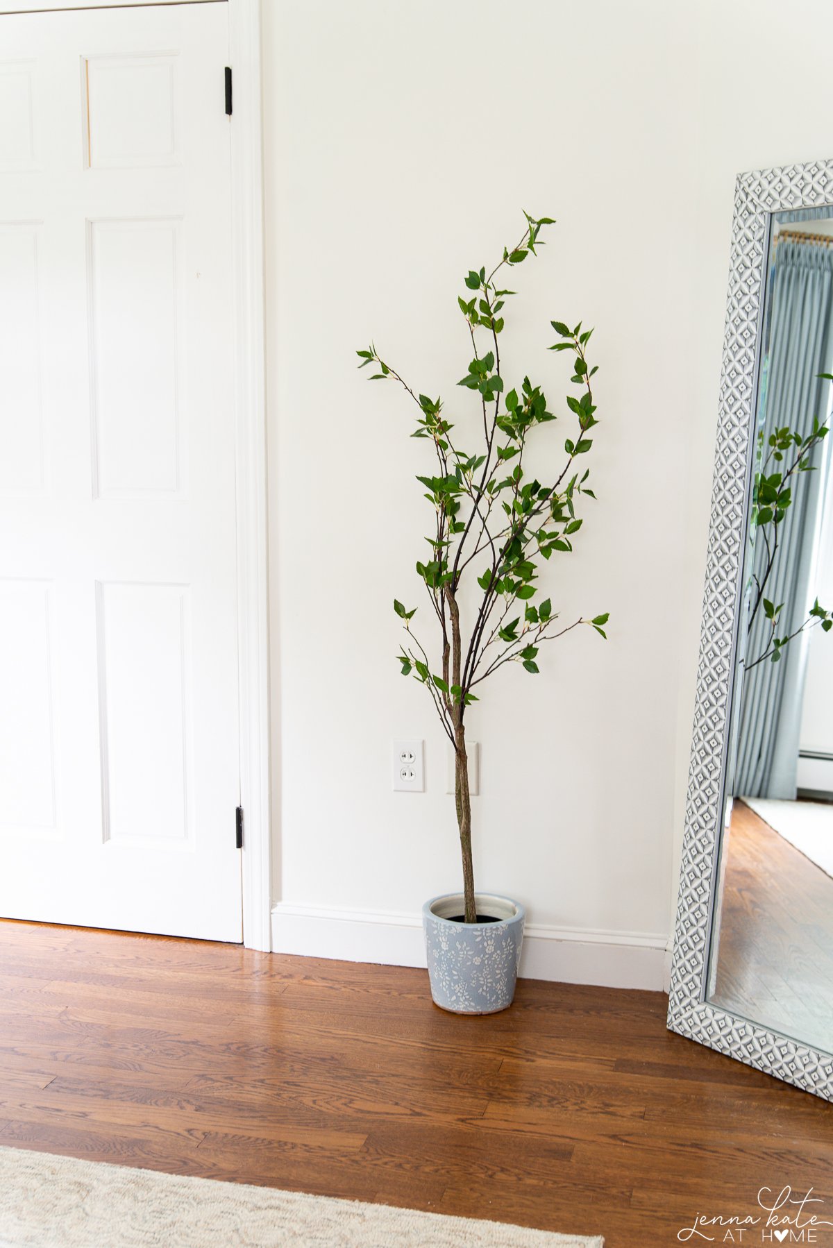 bedroom walls painted white dove with a faux tree in a blue pot in front.
