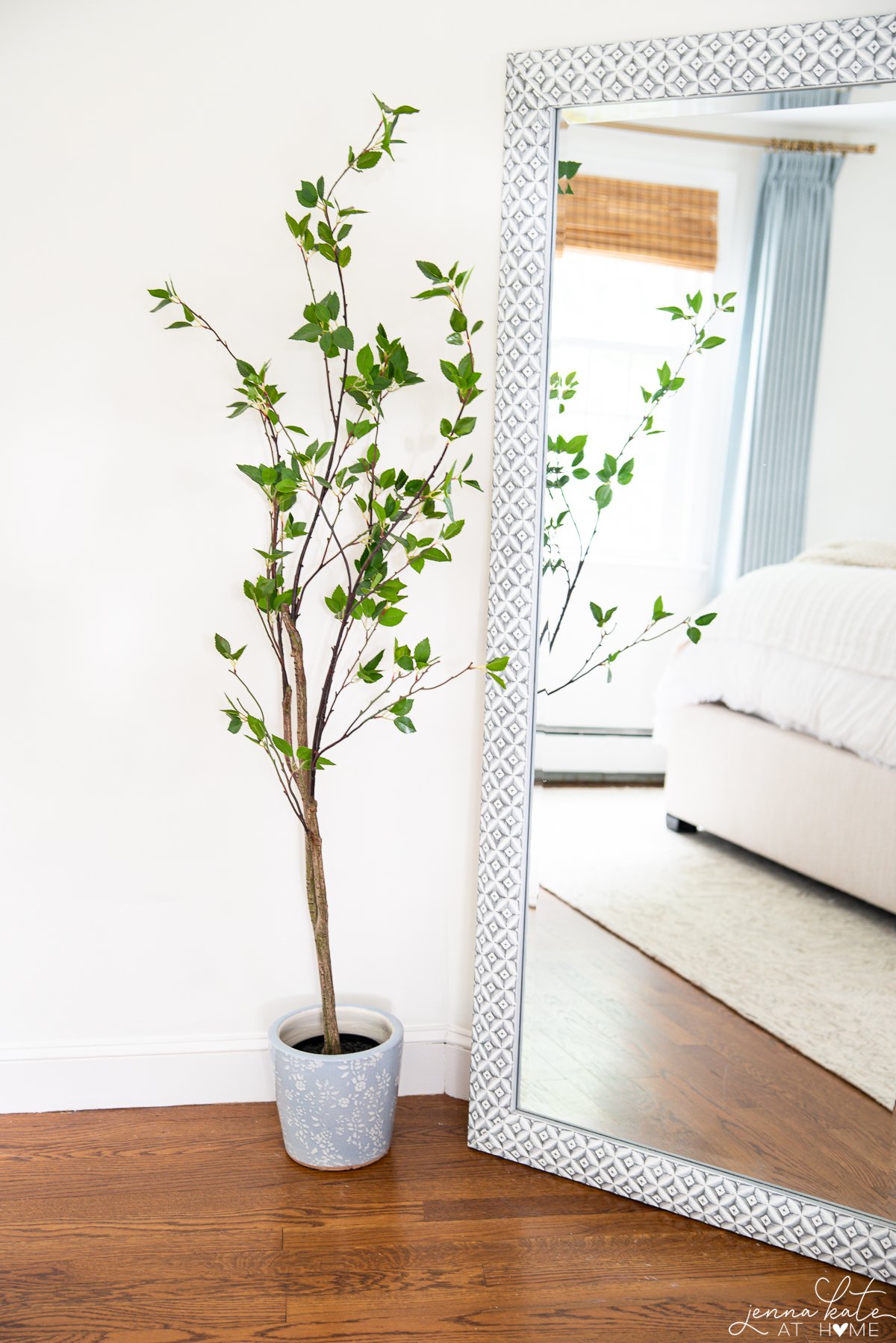 faux tree next to a large floor mirror