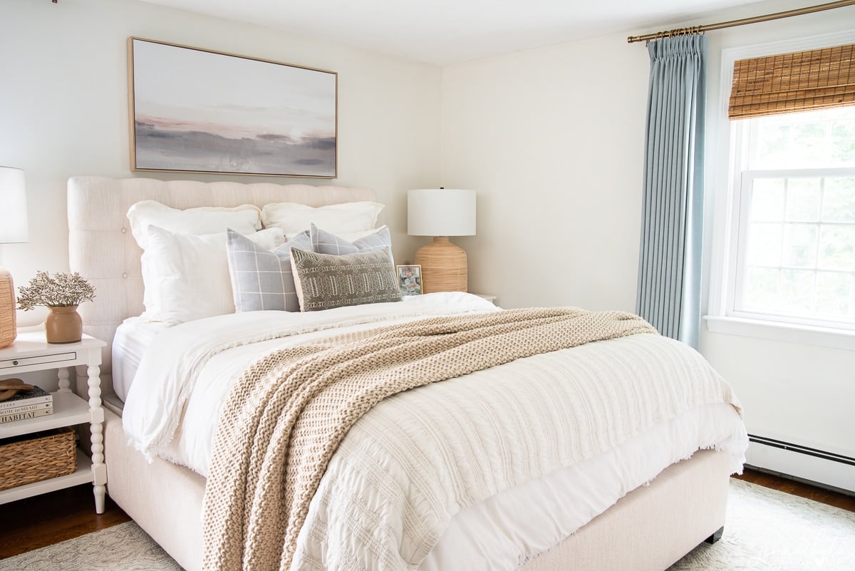 bedroom with neutral bedding and contrasting blue curtains