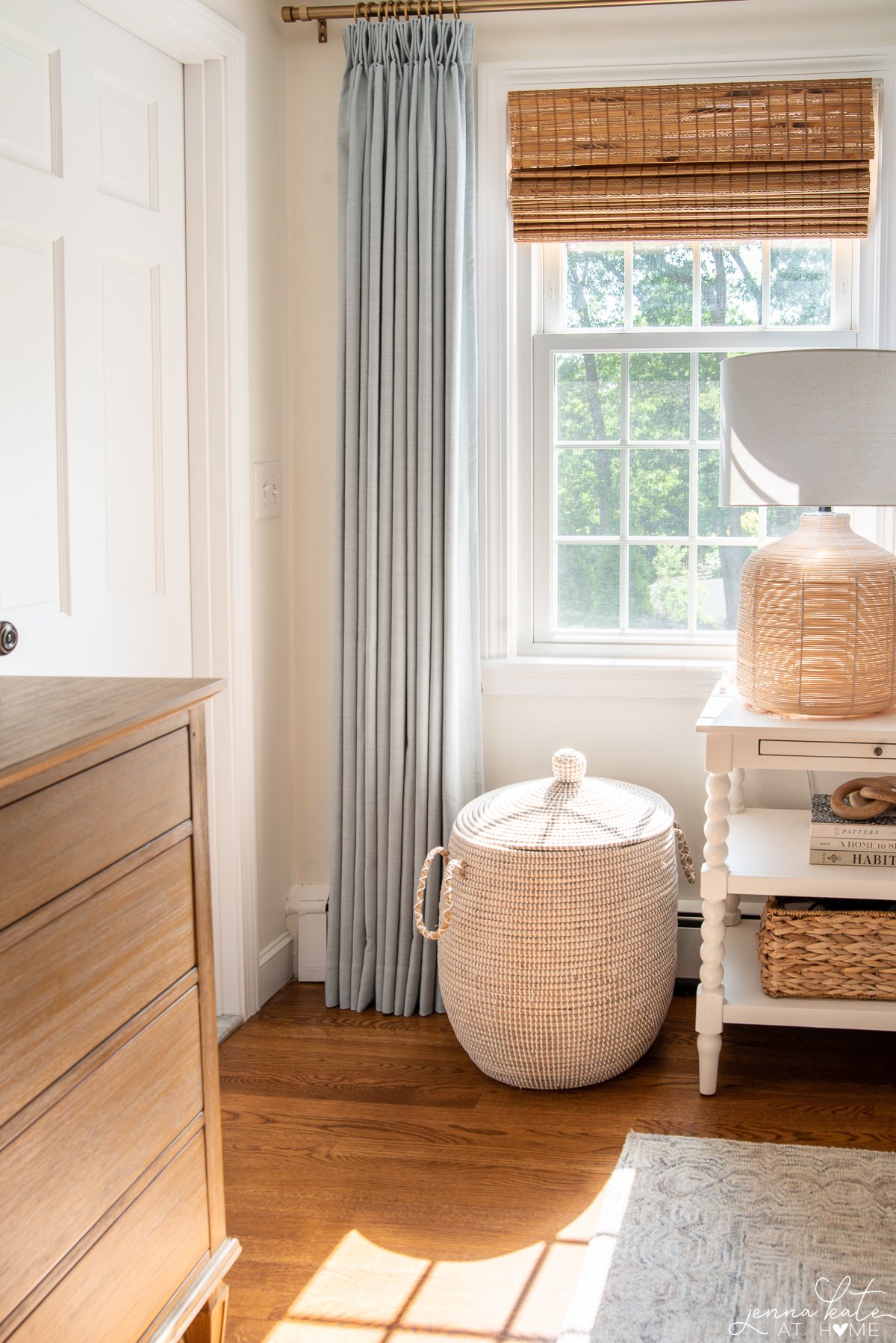 blue curtains and a nightstand with a rattan lamp next to a seagrass basket