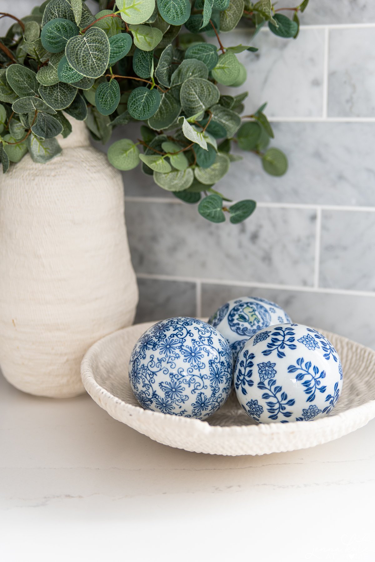 vase ceramic bowl filled with three blue and white decorative balls