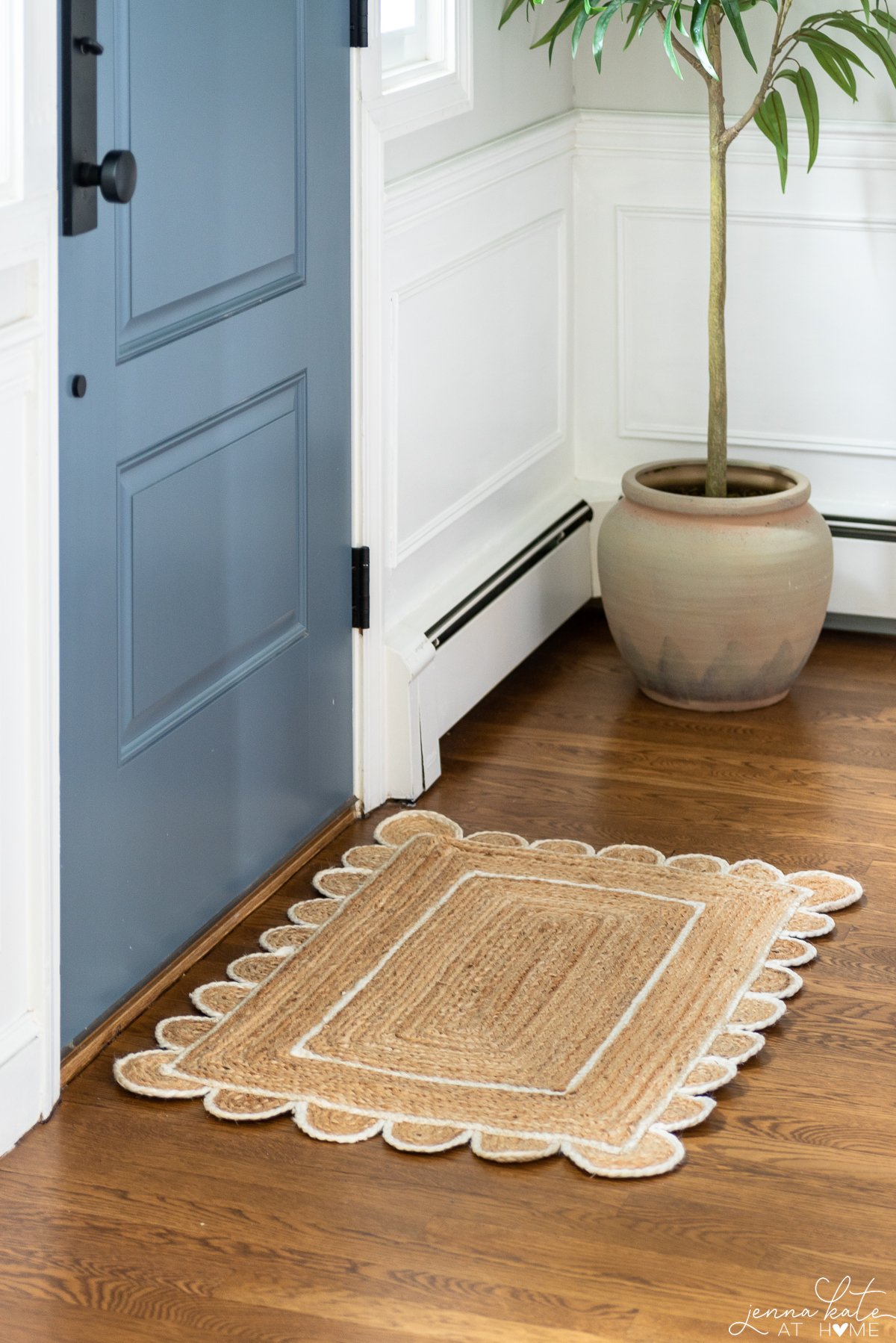 jute and white scalloped doormat next to a blue front door